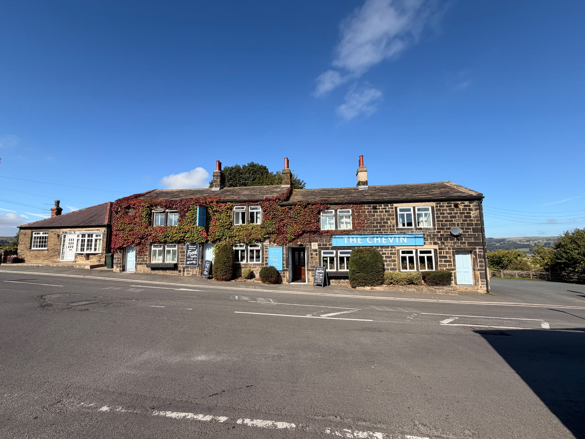 The Chevin Inn stone exterior with ivy and valley beyond